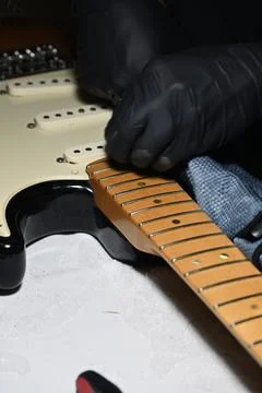 Luthier hands in black protective gloves repairing and polishing electric g.. Stock Photos