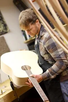 Luthier inspecting handmade guitar in workshop Stock Photos
