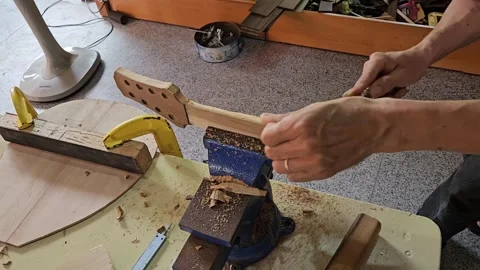 Luthier man's hand holding a chisel to tune an acoustic guitar neck. Stock Footage 282561568
