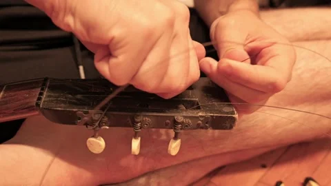 Luthier replacing strings on an old acoustic guitar Stock Footage 341376284