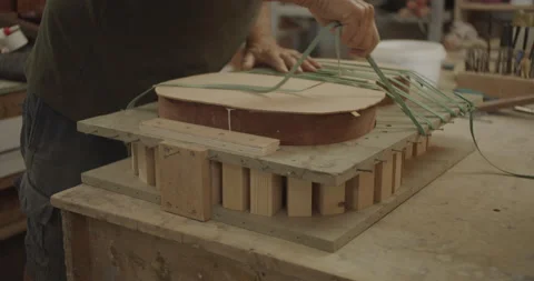 Luthier starching rubber bands over guitar mold Stock Footage 167016961