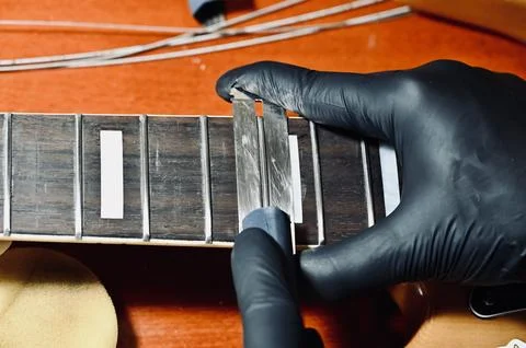 Luthier Using Dual Guards and File on Guitar Frets Stock Photos