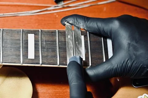Luthier Using Dual Guards and File on Guitar Frets Stock Photos