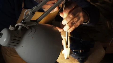 Luthier working intently under a bright lamp, illuminating the fine details of Stock Footage 319483569