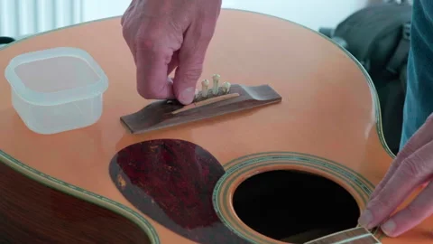 Luthier's hands handle guitar bridge pins with care ready for bridge measur.. Stock Footage 344744799
