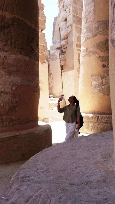 Luxor, Egypt -MARCH 10, 2026: Young tourist woman taking pictures inside karnak Stock Footage 331120351