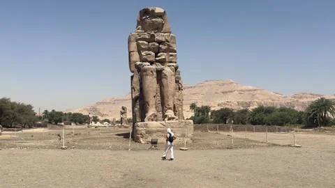 Luxor, Egypt -MARCH 10, 2026: Egyptian guide walking by the colossi of memnon in Vídeos de archivo 331339930