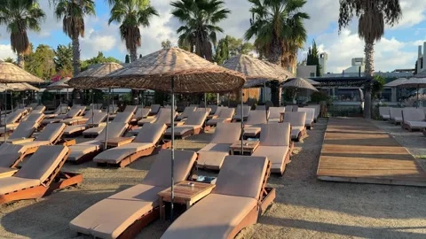 Luxurious beach resort with rows of cushioned sun loungers and straw umbrellas o Stock Footage 329547007