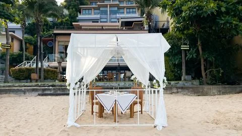 Luxurious beach table setting for a romantic date or wedding proposal Stock Photos
