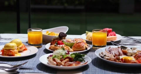 Luxurious breakfast spread on outdoor table, featuring eggs benedict, Видео 318120597