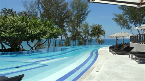 Luxurious infinity pool overlooking ocean at tropical resort, with Видео 275140296