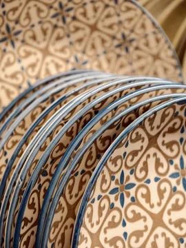 Luxurious patterned ceramic plates with blue rim on shelves in store, close.. Stock Photos