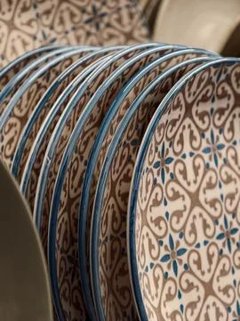 Luxurious patterned ceramic plates with blue rim on shelves in store, close.. Stock Photos
