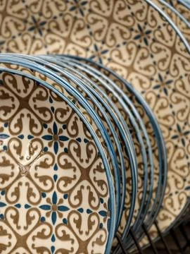 Luxurious patterned ceramic plates with blue rim on shelves in store, close.. Stock Photos