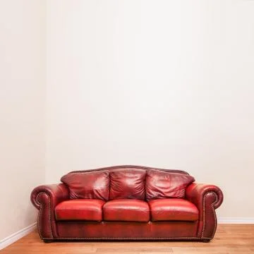 Luxurious red leather couch in front of a blank wall Stock-Fotos