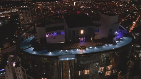 Luxurious rooftop pool area beautifully illuminated at night  vibrant city Stock Footage 297928677