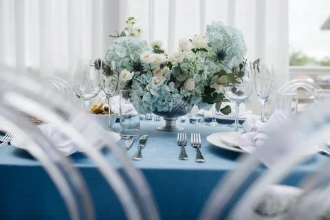 Luxurious round table set for an event, decorated with lush blue bouquets Stock Photos