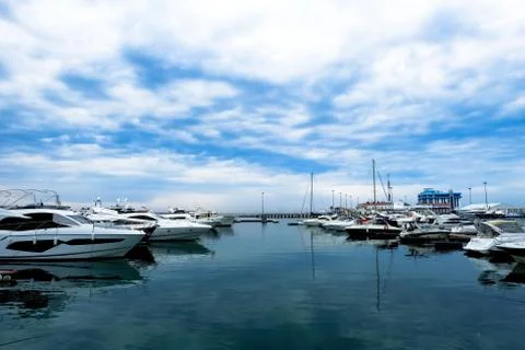 A luxurious view of the sea with a reflection of the clouds. Moored white yac Stock Photos