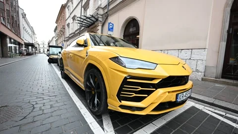 A Luxurious Yellow Lamborghini Urus SUV Parked on a Historic Cobblestone St.. Stock Footage 313871667