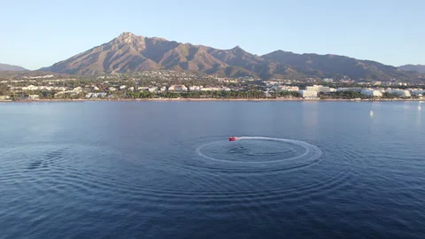 Luxury boat forms a circle of waves with its engines over the sparkling Stock Footage 249757604