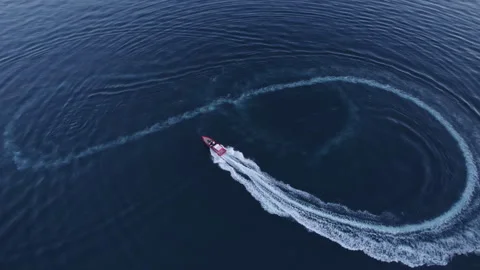 Luxury boat forms a circle of waves with its engines over the sparkling Stock Footage 249757651