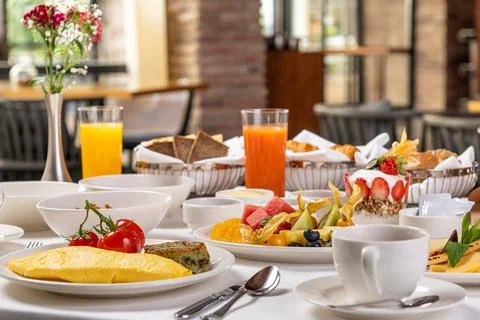 Luxury brunch table with omelette, tomatoes, pastries, fruits and tea Stock Photos