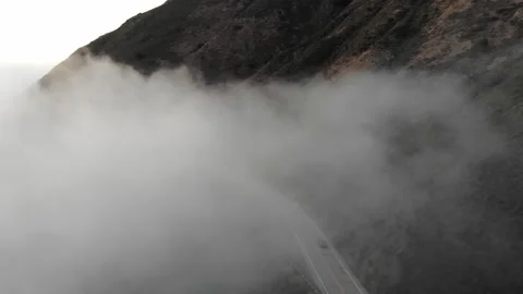 Luxury Car Driving Up Mountain with Clouds at Sunset in Slow Motion, Aerial View Stock Footage 142302194