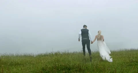 Luxury couple running on the mountain meadow on the background of the fog and Stock Footage 140427770