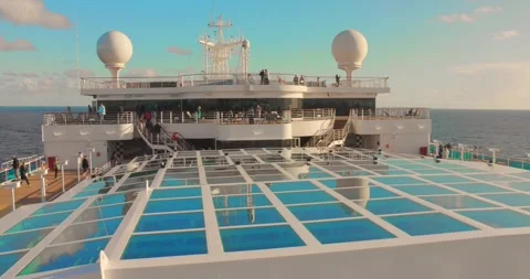 Luxury Cruise Ship Upper Deck Pool Area with White Loungers and Blue Ocean Stock Footage 332647312
