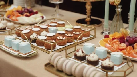 Luxury dessert table with macarons, mini cakes, and fresh fruit platter, elegant Stock Footage 320374430