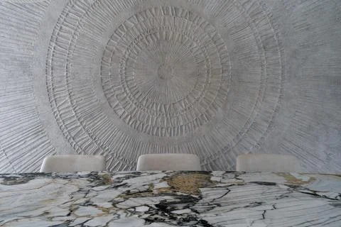 Luxury dining interior with marble table and textured circular wall art Stockfoto's