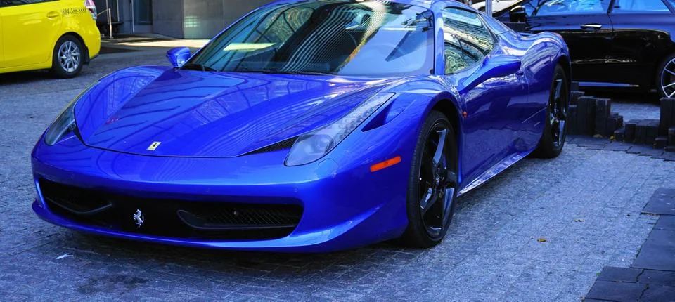 Luxury Ferrari blue car parked at the entrance of Fairmont Pacific Rim hotel. Stock Photos