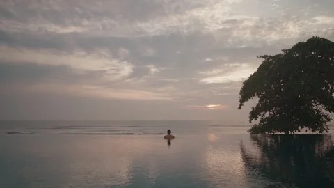 Luxury infinity pool at sunset in Bali with man relaxing ocean view Stockbeeldmateriaal 331061454