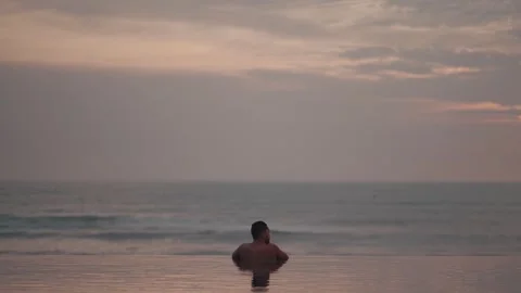 Luxury infinity pool at sunset in Bali with man relaxing ocean view Stockbeeldmateriaal 331065886