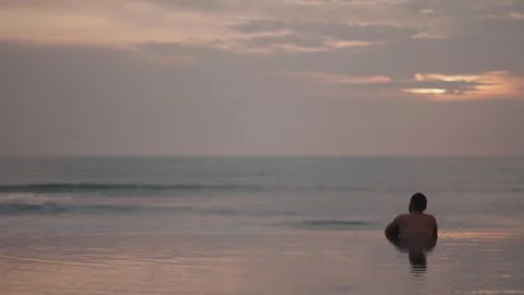 Luxury infinity pool at sunset in Bali with man relaxing ocean view Видео 331066105