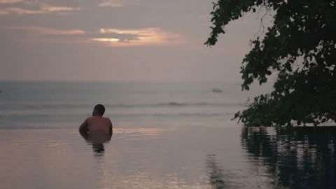 Luxury infinity pool at sunset in Bali with man relaxing ocean view Vidéo 331066419