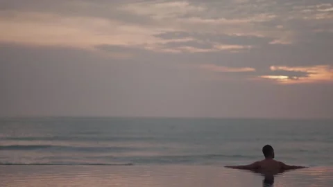 Luxury infinity pool at sunset in Bali with man relaxing ocean view Stock Footage 331066465