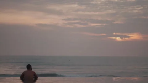 Luxury infinity pool at sunset in Bali with man relaxing ocean view 库存影片 331066604