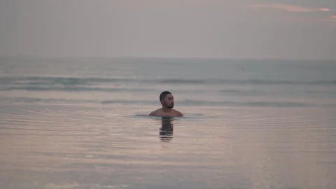 Luxury infinity pool at sunset in Bali with man relaxing ocean view Видео 331066804