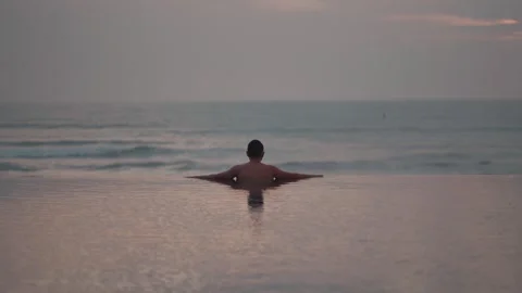 Luxury infinity pool at sunset in Bali with man relaxing ocean view Video stock 331066812