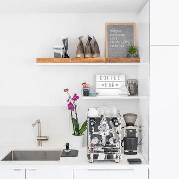 Luxury modern white kitchen with professional barista espresso machine on quartz Stock Photos