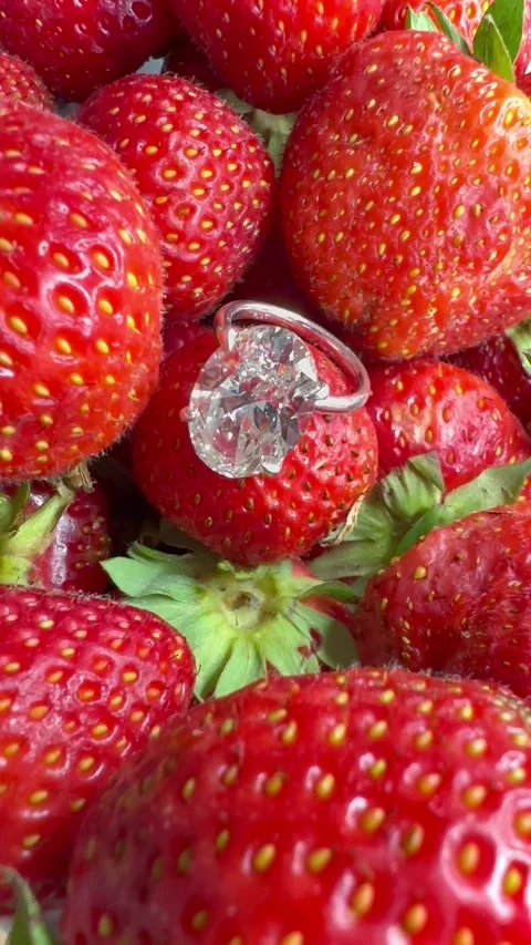 Luxury oval diamond platinum ring among fresh red strawberries Stock Footage 314895291