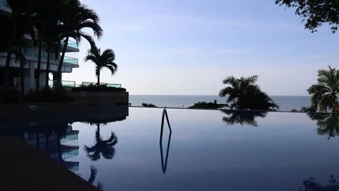 Luxury pool overlooking the ocean with palm trees and modern beachfront Stock Footage 344881720