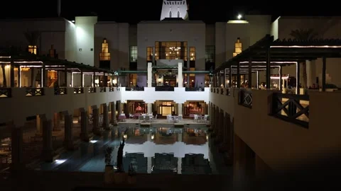 Luxury resort courtyard glows under night lights with elegant columns reflecting 스톡 동영상 310535588