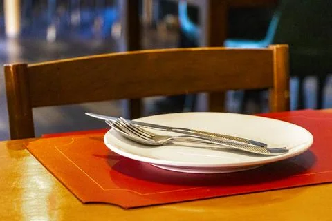 Luxury restaurant table setup with empty plate and silverware arrangement. Stock Photos