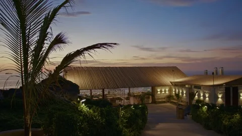 Luxury Seaside Restaurant at Sunset with Palm Trees and Evening Lights Stock Footage 324924486
