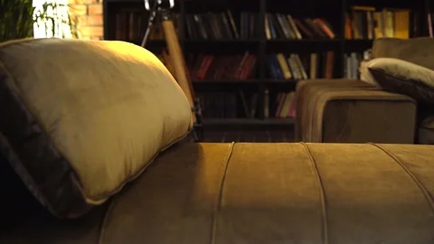 Luxury suede sofa with padded stool in a room with bookshelves Stock Footage 125337138