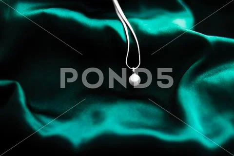 Luxury white gold pearl necklace on dark emerald green silk background, holid Stock Photos
