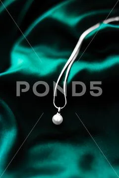 Luxury white gold pearl necklace on dark emerald green silk background, holid Stock Photos