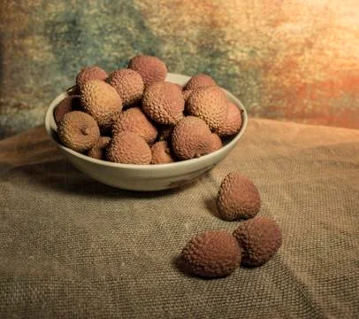 Lychee in a bowl on a dark background, soft light. Tropical fruit lychee Stock Photos